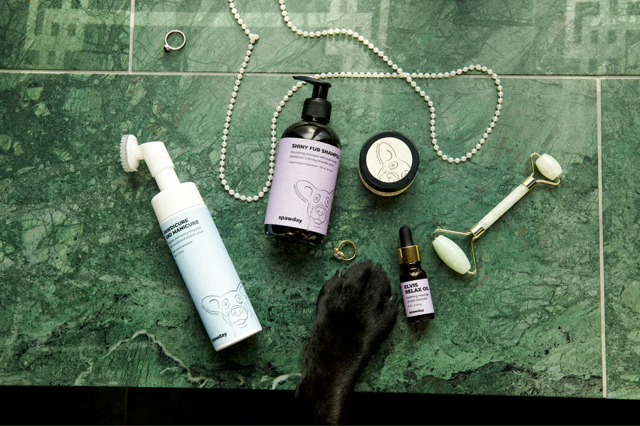 The Spawday range laid out on green marble with a string of pearls, a jade roller and a dog's paw resting in frame